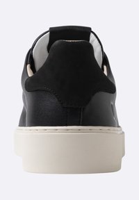 Sneaker in pelle nera con texture liscia, suola in gomma bianca e linguetta del tallone in suede a contrasto. Design semplice, profilo basso.