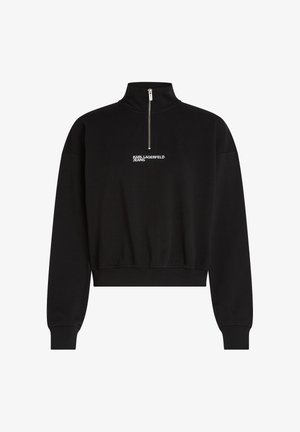 Melnā iezīmētā sporta virsdrēbe ar augstu apkakli, pusciparu, un balto "KARL LAGERFELD JEANS" logo uz krūtīm. Mīksta auduma tekstūra.