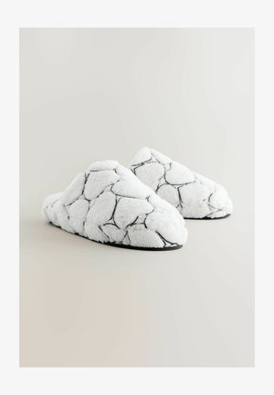 Beli puhasti copati z črnim šivanjem v šestkotnem vzorcu, z mehko teksturo in zasnovo z zaprto peto.