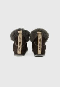 Καφέ μπότες αστραγάλου από σουέντ με γκρι γούνινο περιλαίμιο και μπεζ ετικέτα στη φτέρνα. Διαθέτουν διακριτικό ραφτό σχέδιο και επίπεδη ελαστική σόλα.