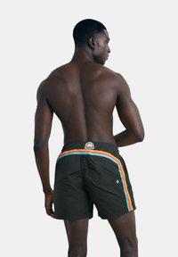 Pantaloni da nuoto neri con un motivo a strisce colorate arancioni e blu sui lati. Presentano una vita regolabile con cordoncino e una patch con logo.