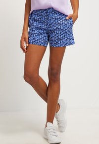 Bermudas florales azules con un diseño ajustado, que presentan una cinturilla sólida y dos bolsillos laterales, confeccionadas en una tela ligera.