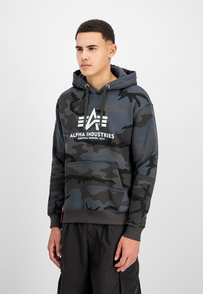 Sötétkék és szürke álcázott kapucnis pulóver, elülső kenguruzsebbel, állítható kapuccsal, és fehér logós szöveggel a mellrészen. Bordázott mandzsetták és derék.