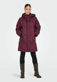 Mørkerød polstret parka med høj krave, lynlåslommer og knaplukning, der har et quiltet mønster og en tætsiddende silhuet.