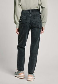 Jeans de denim gris oscuro con corte recto, que cuentan con dos bolsillos traseros y una cintura alta. Llevados con zapatos verde claro y una blusa a juego.