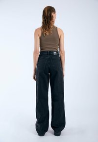 Donkerdenim wijde jeans met een hoge taille, voorzien van een textuur en achterzakken. Gepaarde met een bruine tanktop.
