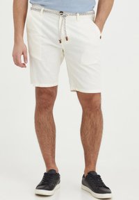 Hvite shorts laget av lett materiale, med to sidelommer, en vevd snøring med brune detaljer, og en avslappet passform.
