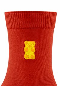 Rote gestrickte Socke mit geripptem Bund, versehen mit einer gelben Gummibärchen-Stickerei an der Seite. Weicher Stoff, mittlere Dicke.