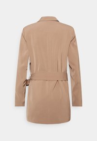 Trench-coat beige ceinturé avec col châle, manches longues et coupe droite, présentant une texture de tissu lisse et un design minimaliste.