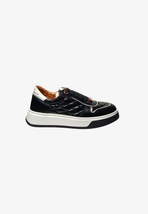 Baskets en cuir matelassé noir avec semelle blanche et fond en caoutchouc texturé noir. Présente des accents bruns et des lacets noirs.