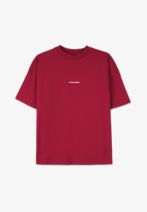 Burgundska bombažna majica z ohlapnim krojem, kratkimi rokavi in belim napisom "PEGADOR" spredaj. Gladek tekstura, okrogli izrez.
