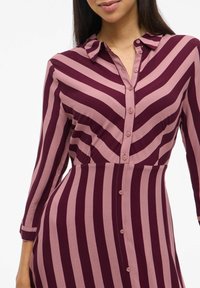 Knopf-up Kleid mit vertikalen Streifen in tiefem Burgunderrot und sanftem Pink. Hergestellt aus glattem Stoff, verfügt es über einen Kragen und lange Ärmel.