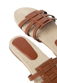 Braune Leder-Sandalen mit einem geflochtenen Riemendesign und kontrastierender Naht. Strukturiertes Seil-Fußbett und glatte, abgerundete Sohle.