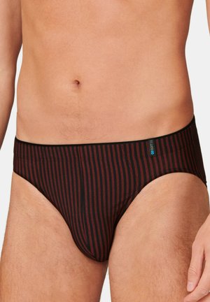 Mężczyzna noszący czarne i ciemnoczerwone majtki w pionowe paski z małą naszywką z logo na pasku w talii.