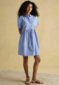 Sinine lühikeste varrukatega kleit nööpidega krae, õmmeldud vöökoht ja valge lillemuster. Kandmine kergete sandaalidega.