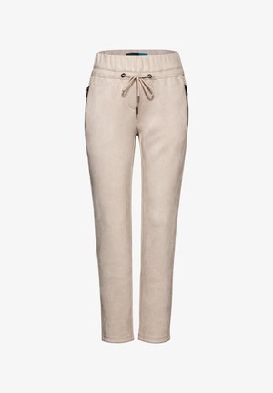 Pantalons de survêtement beige en matériau doux. Dotés d'une taille élastique, d'un cordon de serrage et de poches zippées sur les côtés. Coupe slim avec chevilles fuselées.