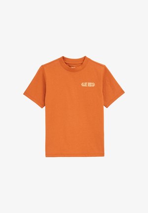 Pomarańczowa bawełniana koszulka z krótkimi rękawami, okrągłym dekoltem i małą białą grafiką na lewej piersi. Gładka tekstura i swobodny design.