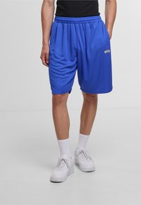 Blå atletiske shorts lavet af åndbart stof; har en elastisk talje, sidelommer og hvid skrift på fronten.