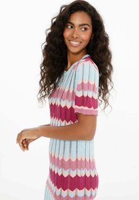 Sukienka dzianinowa z wzorem w zygzak w pastelowych odcieniach niebieskiego, różowego i fioletowego. Krótkie rękawy, prążkowana faktura i dopasowany krój.