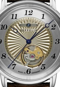 Zeppelin automatic watch with a silver textured dial, blue hands, and black numerals; visible gold and silver movement. Brown leather strap.