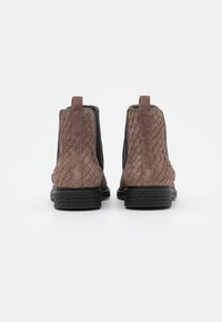 Bottines en daim marron avec texture tissée sur les côtés, panneaux élastiques noirs et semelle en caoutchouc durable.