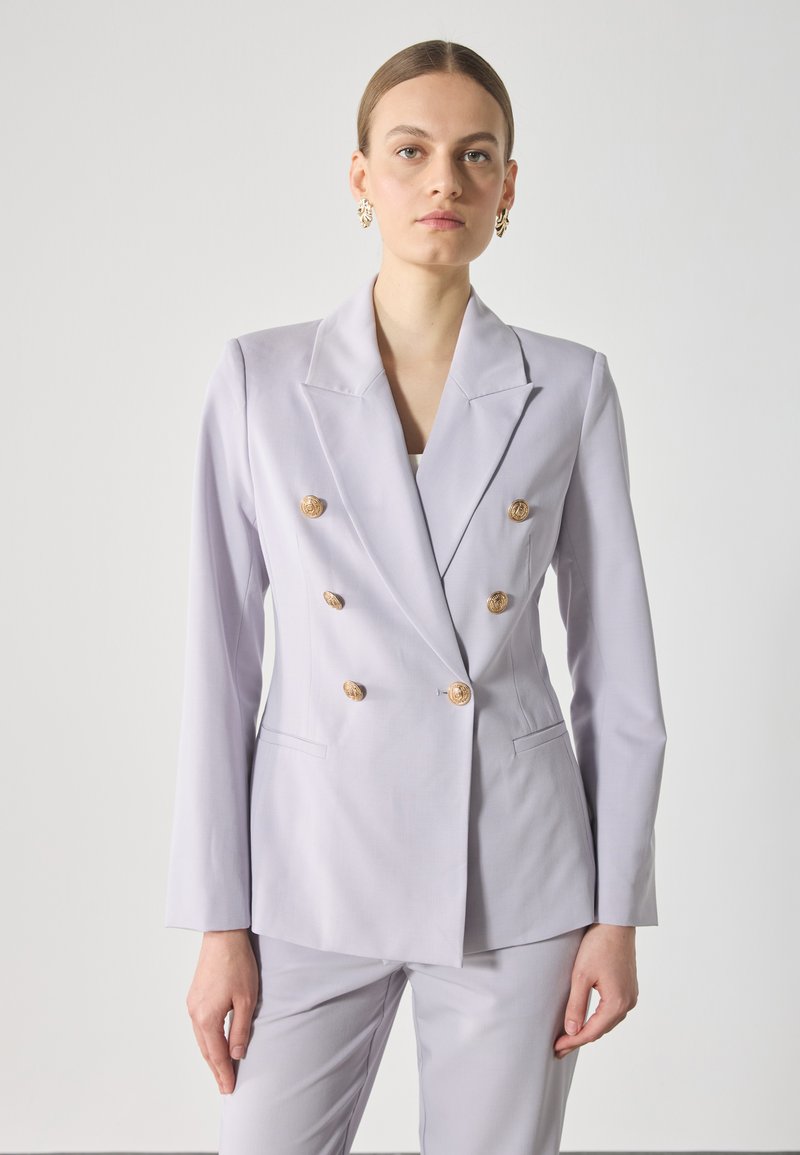 Blazer doppiopetto in lavanda chiaro con bottoni circolari dorati, revers strutturati e maniche lunghe. Vestibilità aderente con tasche laterali.