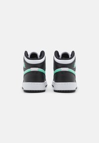 Tenisky vysokého střihu s černým koženým svrškem, bílou podrážkou a zelenými akcenty. Mají polstrovaný límec a strukturovanou gumovou podrážku.