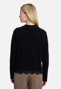 Czarny sweter z koronkowym wykończeniem na dole, teksturowanej dzianiny, z okrągłym dekoltem i długimi rękawami. Prosty i elegancki design z misternymi detalami z koronki.