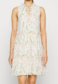 Abito senza maniche a fiori con scollatura a chiave, dettagli arricciati, gonna a strati e una palette di colori pastello con motivi rosa e verdi.