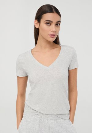 T-shirt grigio in cotone a maniche corte con scollo a V, caratterizzato da una texture morbida e una vestibilità rilassata. Al centro del modello su uno sfondo neutro.