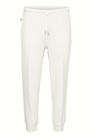 Valged dressipüksid, millel on nööriga vöökoht, kitsenev lõige ja küljetaskud. Valmistatud pehmest, siledast kangast, millel on õrn läige.