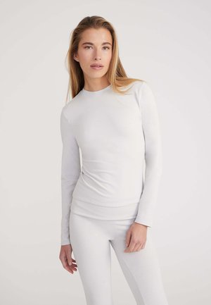 Helles graues Langarmoberteil mit Rundhalsausschnitt, figurschmeichelndem Design und glatter Textur, kombiniert mit passenden, figurbetonten Leggings. Minimalistisches Styling.