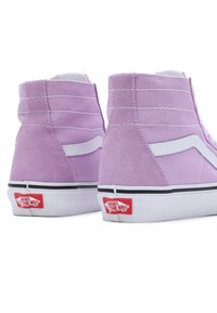Zapatillas de deporte altas moradas que combinan materiales de ante y lona, con acentos blancos, un cuello acolchado y un logo rojo de Vans en el talón.