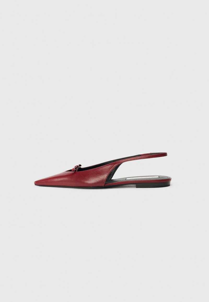 Κόκκινο δερμάτινο παπούτσι slingback με μυτερή μύτη, επίπεδο τακούνι και μικρή φιόγκο μπροστά. Λείος υφή και μινιμαλιστικός σχεδιασμός.