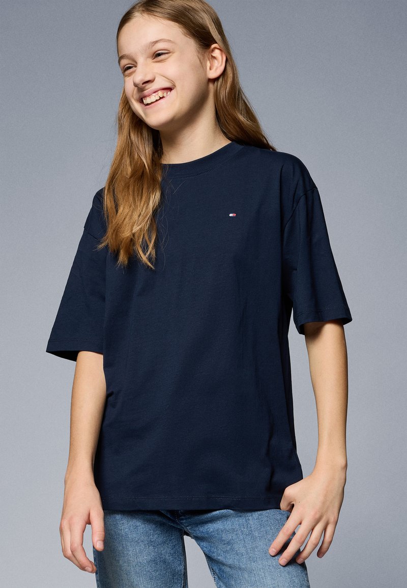 Navyblaues Baumwoll-T-Shirt mit kurzen Ärmeln, Rundhalsausschnitt und einem kleinen Logo auf der Brust. Kombiniert mit hellblauen Jeans.
