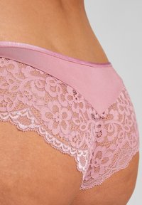 Roze kanten slipjes met een zachte stof tailleband en een ingewikkeld bloemenkant ontwerp langs de randen, met geschulpte details.