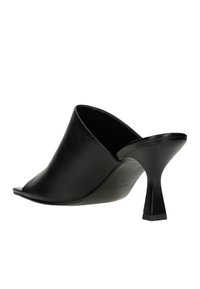 Mule aperti in pelle nera con tacco alto a punta. Il design presenta una texture liscia e una silhouette slanciata e sagomata.