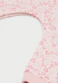 Różowy kombinezon z motywem serca i panterki, z zapięciami na zatrzaski i miękkim bawełnianym materiałem. Rękawy wykończone jednolitym różowym kolorem.