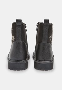 Stivali alla caviglia neri con tacco in pelle texturizzata e parte superiore in tessuto con ricami floreali. Chiusura con zip su ciascun lato. Suola piatta in gomma.