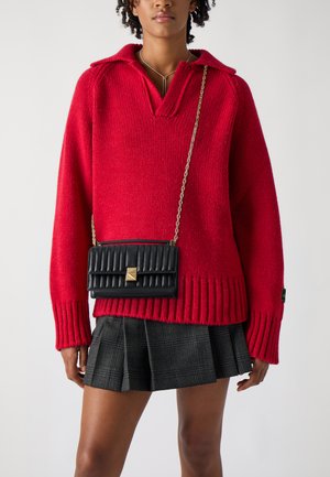 Red knitted sweater with a collar, paired with a black quilted crossbody bag featuring a gold accent. Gray plaid pleated skirt completes the outfit.