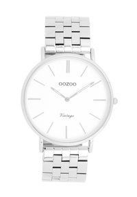 Montre en acier inoxydable argenté avec un cadran blanc rond, des marqueurs argentés minimalistes et un bracelet en maille. Comprend le texte "OOZOO Vintage" en bas.