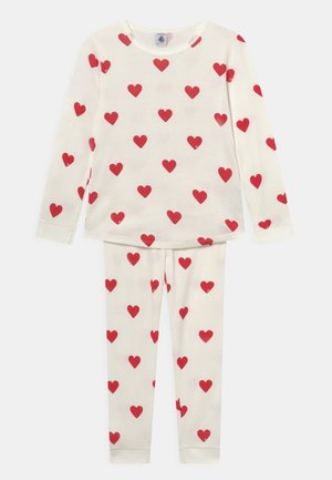 Set i bomull med pyjamas som har långärmad topp och byxor, båda i krämfärg med röda hjärtan, rund halsringning och åtsittande ärmslut.