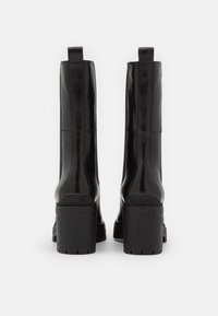 Black leather ankle boots with a block heel, smooth texture, and rear pull tabs. Features vertical seam details and a treaded sole.