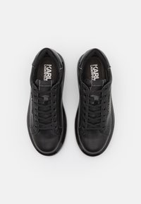 Zwarte leren sneakers met een ronde neus, vetersluiting aan de voorkant, gevoerde kraag en logo-accenten aan de zijkanten. Gladde textuur en een laag profiel ontwerp.