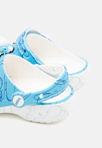 Blue clogs feature a textured upper with white accents, playful graphic designs, and a contrasting white sole with rounded edges.