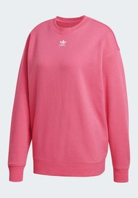 Rosa sweatshirt i mjuk bomullsblandning, med rund halsringning, neddragna axlar och en vit Adidas-logotyp på bröstet.