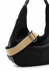 Sac à main en cuir noir avec une finition texturée, doté d'une large bandoulière beige et de garnitures en argent. Forme arrondie, coutures latérales visibles.