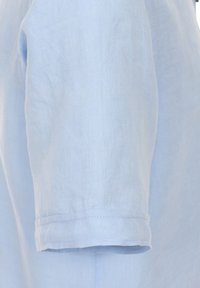 Light blue linen short-sleeve shirt, with a soft texture and neat hemline. Fabric appears breathable and lightweight.