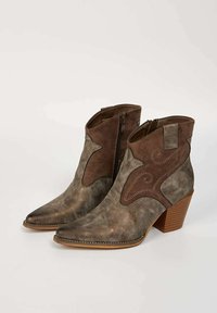 Bottines en suede marron, à bout pointu, avec fermeture éclair et coutures décoratives sur les côtés. Talon empilé avec une texture bois.