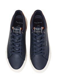 Zapatillas de cuero azul marino para hombre con suelas de goma beige, que presentan una lengüeta marrón a contraste, cordones texturizados y el logo en el lateral y la lengüeta.